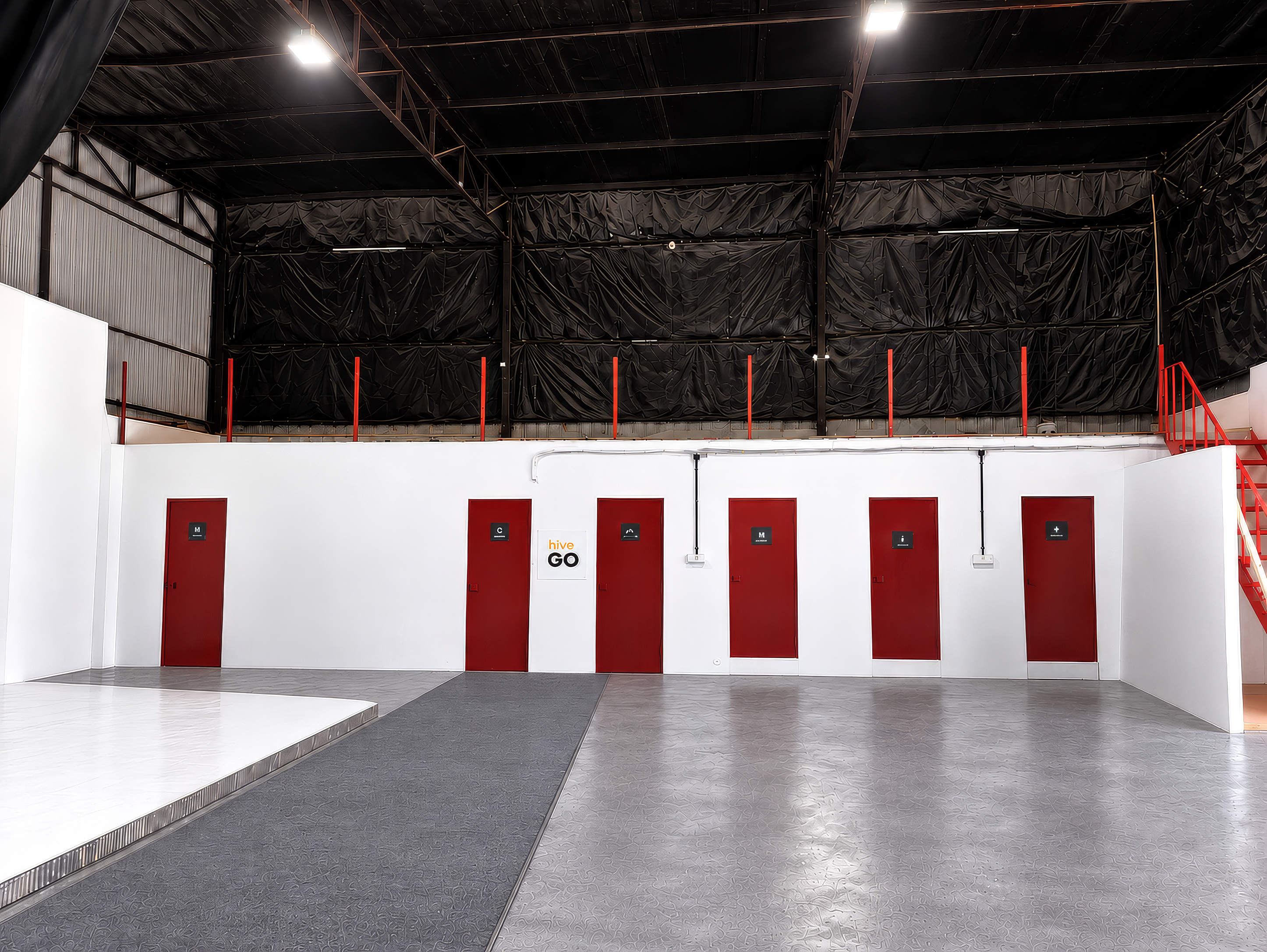 Hive by Go studio floor with red doors, branded wall and a black draped ceiling
